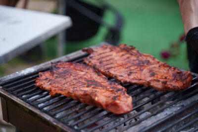 Juicy grilled steaks sizzling on an outdoor charcoal barbecue with vibrant summer vibes.